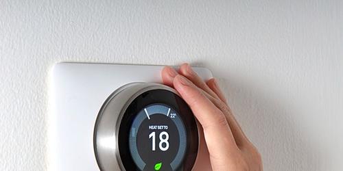 Hand adjusting a heating thermostat with temperature displayed as 18
